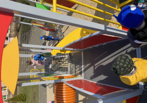 Chłopiec przechodzi po drewnianej kładce, dwoje dzieci przechodzi po "linowe kratownicy".j