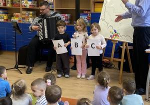 Troje dzieci prezentuje litery A B C w nawiązaniu do książki edukacyjnej "ABC młodego Polaka".