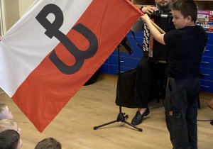 Chłopiec demonstruje flagę powstania warszawskiego.