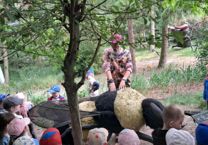 Dzieci oglądają realistyczną, gigantyczną rzeźbę pszczoły.