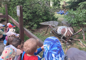 Dzieci oglądają realistyczną, gigantyczną rzeźbę muchy.