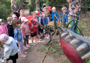 Dzieci oglądają realistyczną, gigantyczną rzeźbę pluskwy.