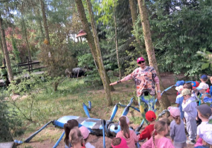 Dzieci oglądają realistyczną, gigantyczną rzeźbę modliszki.