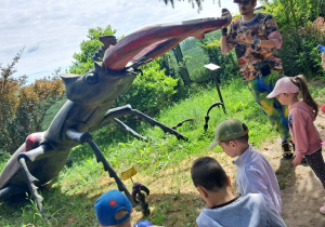 Dzieci oglądają realistyczną, gigantyczną rzeźbę chrząszcza rohatyńca.