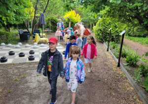 Dzieci idą ścieżką edukacyjną z przewodnikiem