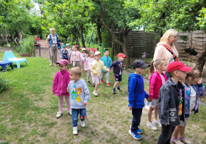 Dzieci idą ścieżką edukacyjną z przewodnikiem