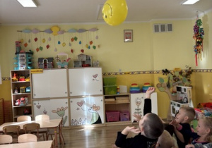 Dzieci odbijają balon tak by nie spadła na dywan.