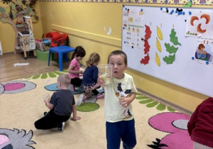 Dzieci dmuchając piórko do góry łapią je do kubeczka.