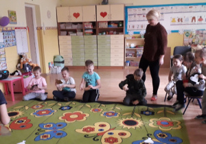 Dzieci siedzą na dywanie podczas zajęć