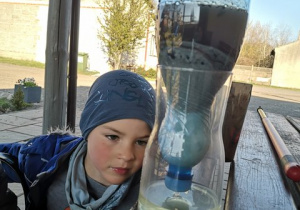 Chłopiec wykonał filtr i obserwuje oczyszczanie wody