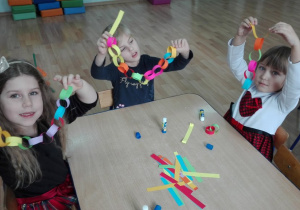 Dzieci wykonują z pasków kolorowy łańcuch
