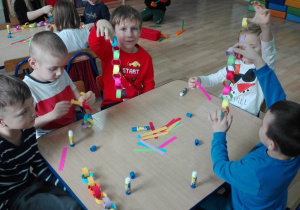 Dzieci wykonują z pasków kolorowy łańcuch