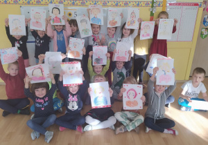 Wszystkie dzieci prezentują narysowane portrety babć.