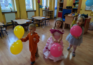 Dzieci trzymają baloniki.
