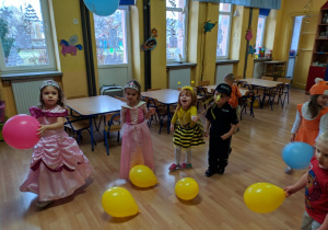 Dzieci stoją z kolorowymi balonami.