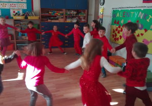 Dzieci tańczą w dużym kole trzymając się za ręce.