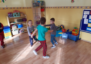 Dzieci tańczą w małych kółeczkach do muzyki.