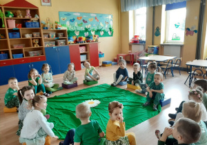 Dzieci siedzą na dywanie i słuchają listu od Pani Wiosny.