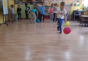 Dzieci ścigają się przesuwając balon za pomocą łapki na muchy