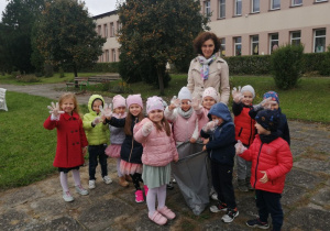 Grupa Pszczółki stoi z workiem zebranych śmieci.