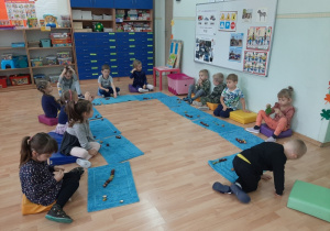 Dzieci układają na dywanikach kasztany, żołędzie i orzechy