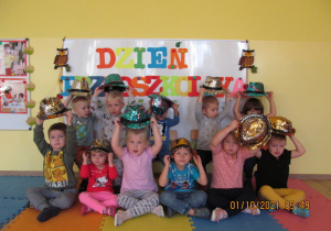 Dzieci pozują do zdjęcia podnosząc kapelusze nad głowami