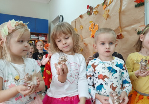 Dzieci prezentują zawieszki z dużymi, złotymi wiewiórkami