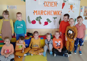 Dzieci pozują do zdjęcia przy tablicy z napisem Dzień Marchewki