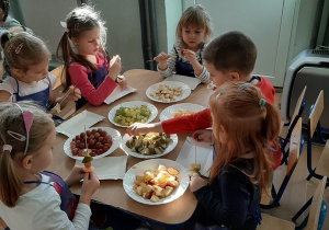 Dzieci nakładają owoce na patyczki szaszłykowe