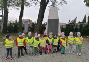 Przedszkolaki stoją przed tablicą upamiętniającą nazwiska poległych żołnierzy