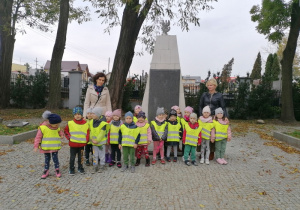 Przedszkolaki stoją przed tablicą upamiętniającą nazwiska poległych żołnierzy