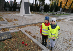 Dzieci stawiają na grobie znicze