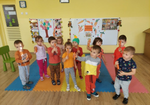 Przedszkolaki pokazują trzymane marchewki
