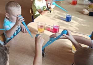 Dzieci wlewają zabarwioną wodę do kubka z olejem