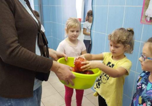 Dziewczynki myją owoce i warzywa.