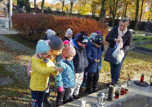 Dzieci czekają na znicze, aby postawić je na grobie