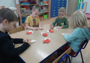 Dzieci ozdabiają białe i czerwone liście
