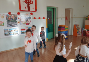 Dzieci trzymają liście w kolorach flagi i tańczą