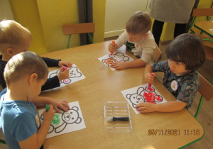 Dzieci wykonują prace plastyczną - stemplują misie kolorowymi farbami