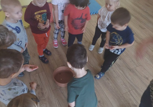 Dzieci rzucają grosik do miski z wodą