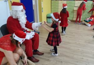 Mikołaj częstuje dziewczynkę czekoladką