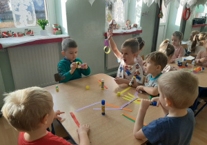 Dzieci sklejają paski tworząc łańcuch choinkowy.