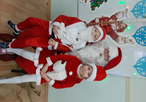 Dwoje dzieci pozuje do zdjęcia z Mikołajem.