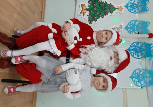 Dwoje dzieci pozuje do zdjęcia z Mikołajem.