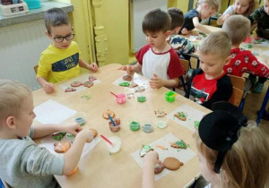 Dzieci dekorują ciastka i przyglądają się tym wykonanym jak smacznie wyglądają