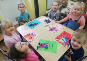 Dzieci przy stolikach prezentują wykonane pajączki