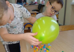 Chłopcy sprawdzają co przyciągnie naelektryzowany balon