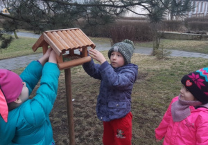 Dzieci dosypują ziarna do karmnika