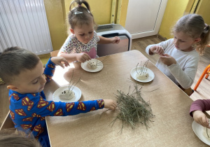 Dzieci wkładają sosnowe igły w ciastolinowe jeże