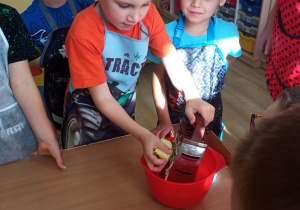 Dzieci ucierają jabłko na tarce.
